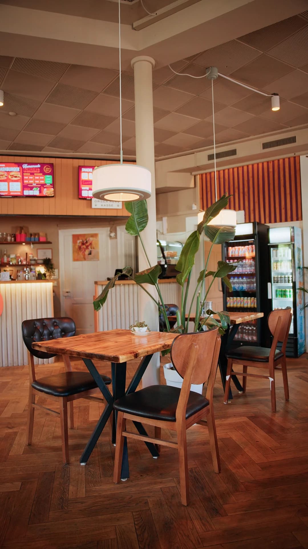 Inside the restaurant: wooden tables, warm light, menu boards above the counter