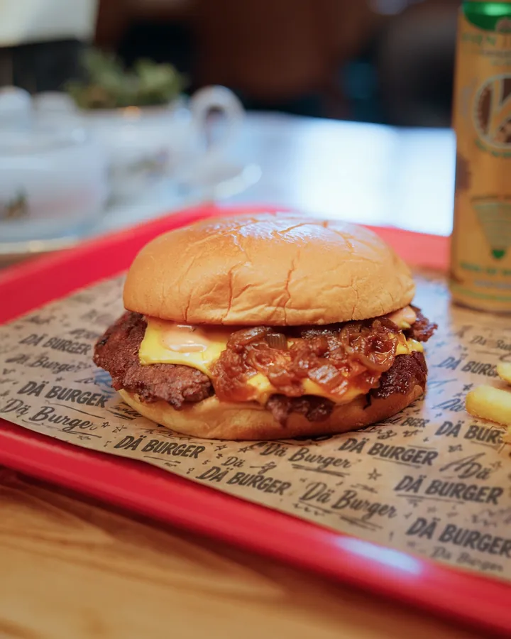 A smashburger with fries on the red tray with DÄ burger paper